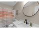 Well-lit bathroom with a round mirror, framed art, and decorative shower curtain at 109 N Valley Dr, Louisburg, NC 27549