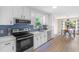Bright kitchen features white cabinets, stainless steel appliances, and blue tile backsplash at 109 N Valley Dr, Louisburg, NC 27549
