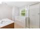 Bright bathroom featuring a garden tub, separate shower, and a large window at 11710 Mezzanine Dr # 101, Raleigh, NC 27614