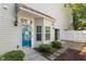 Inviting townhome entrance featuring a bright blue door, manicured landscaping, and a charming covered porch at 11710 Mezzanine Dr # 101, Raleigh, NC 27614