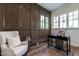 Home office with wood paneling, a black desk, accent chair and a view of the trees at 1222 Duplin Rd, Raleigh, NC 27607