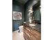 This powder room features dark teal walls with white floors, a wooden vanity, and a black marble countertop at 1222 Duplin Rd, Raleigh, NC 27607