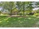 Spacious backyard with lush green grass and shade trees, showcasing the brick home at 129 Trellingwood Dr, Morrisville, NC 27560