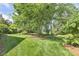 Serene backyard featuring well-maintained lawn and mature trees, offering a sense of privacy and space at 129 Trellingwood Dr, Morrisville, NC 27560