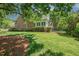 Backyard view of brick home with manicured lawn and lush landscaping, including a covered outdoor area at 129 Trellingwood Dr, Morrisville, NC 27560