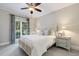 Sunlit bedroom featuring neutral tones, a comfortable bed, and a view of the landscaped yard at 129 Trellingwood Dr, Morrisville, NC 27560