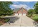 Spacious three-car garage made of brick with an extensive driveway surrounded by green vegetation at 129 Trellingwood Dr, Morrisville, NC 27560