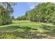 Picturesque golf course view showcasing lush fairway and mature trees under a clear blue sky at 129 Trellingwood Dr, Morrisville, NC 27560