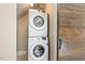 Convenient laundry closet with stacked washer and dryer unit and adjacent rustic sliding barn door at 129 Trellingwood Dr, Morrisville, NC 27560