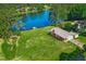 Aerial view of lakefront home with lush lawn, boathouse, brick house, and mature trees at 1415 Clearwater Dr, Sanford, NC 27330