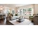 Bright and airy living room featuring a comfortable sofa, large windows, and a view into the adjacent kitchen at 1428 Goldfinch Perch Ln, Knightdale, NC 27545