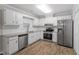 Bright kitchen features white cabinets, stainless appliances, granite countertops, and wood-look flooring at 1442 Aversboro Rd # 7, Garner, NC 27529