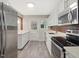 Modern eat in kitchen with stainless steel appliances, gray tile floor, quartz countertop, and white cabinets at 1521 N Duke St, Durham, NC 27701
