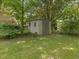Backyard view featuring a shed with neutral siding and double doors, surrounded by a lush green lawn at 1521 N Duke St, Durham, NC 27701