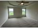 A bright bedroom with a tray ceiling, ceiling fan, neutral carpet, and two windows at 167 Lotus Ave, Smithfield, NC 27577