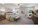 Spacious bedroom featuring a plush bed, ceiling fan, sitting chair, and natural light from bright windows at 1931 Ballard Rd, Fuquay Varina, NC 27526