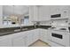 Well-lit kitchen showcasing granite countertops, white cabinetry and appliances, and a view into the living area at 1933 Castle Pines Dr, Raleigh, NC 27604