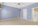 Large bedroom with neutral carpet leading to bathroom; ceiling fan and blue paint create a calming atmosphere at 2089 White Pond Ct, Apex, NC 27523