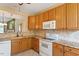 This kitchen has wooden cabinets, granite countertops, and white appliances at 2089 White Pond Ct, Apex, NC 27523