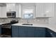 Modern kitchen with white countertops, blue lower cabinets, stainless appliances and a sunlit window at 2407 Miriam Cir, Durham, NC 27704