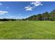 A beautiful green grassy lot with a house in the background against a cloudy blue sky at 253 Lotus Ave, Smithfield, NC 27577