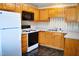 Efficient kitchen with wooden cabinets, white appliances, and black and white linoleum flooring at 3027 Maple Ave # Apt K3, Burlington, NC 27215