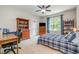 Well-lit bedroom with a plaid bedspread, wooden desk, and organized bookcase at 304 Villa Dr, Durham, NC 27712