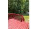 Spacious deck area with red railings and a view of the grassy backyard and mature trees at 3609 Cold Harbour Dr, Raleigh, NC 27610