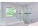 Modern bathroom featuring a glass-enclosed shower, tub, and a bright window at 401 Robert Hunt Dr, Carrboro, NC 27510