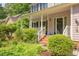 Inviting front porch with brick steps, white railings, and lush landscaping, offering curb appeal at 401 Robert Hunt Dr, Carrboro, NC 27510