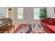 Bright living room featuring a piano, hardwood floors, large windows, and a colorful area rug at 401 Robert Hunt Dr, Carrboro, NC 27510