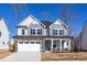 Charming two-story home featuring a stone-accented garage, gray siding, and an inviting front porch with an American flag at 416 Longleaf Glen Ln, Zebulon, NC 27597