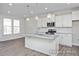 Modern kitchen featuring a marble island, stainless steel appliances, white cabinets, and hardwood floors at 416 Longleaf Glen Ln, Zebulon, NC 27597