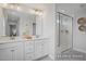 Well-lit bathroom with double vanity, quartz countertop, and glass enclosed shower at 420 Longleaf Glen Ln, Zebulon, NC 27597