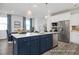 Modern kitchen features a blue island with a white countertop, stainless steel appliances, and stylish pendant lighting at 420 Longleaf Glen Ln, Zebulon, NC 27597