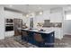 Spacious kitchen with a large island, white cabinetry, stainless steel appliances, and modern pendant lighting at 420 Longleaf Glen Ln, Zebulon, NC 27597