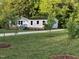 Quaint home with a gravel driveway, surrounded by green grass and young trees at 550 Saplin Branch Rd, Timberlake, NC 27583