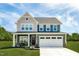 Two-story home with a two-car garage, covered porch and manicured lawn under a bright blue sky at 569 Freedom Trail Dr, Willow Springs, NC 27592