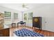 Inviting bedroom featuring hardwood floors, a ceiling fan, and natural light from three windows at 704 Valleywater St, Fuquay Varina, NC 27526