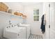 Well-lit laundry room with side-by-side washer and dryer and overhead storage shelves at 704 Valleywater St, Fuquay Varina, NC 27526