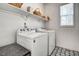 Well-lit laundry room featuring a washer and dryer with patterned tile flooring, and storage shelves at 704 Valleywater St, Fuquay Varina, NC 27526