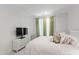 Minimal bedroom features a bed with white bedding, a dresser with a TV, and bright curtains at 810 Maple Berry Ln # 104, Raleigh, NC 27607