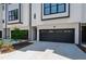 Modern townhome exterior with black garage doors, white siding, and fresh landscaping at 810 Maple Berry Ln # 104, Raleigh, NC 27607