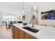 Kitchen island featuring a stainless steel sink, brass faucet, and seating, with a view of the dining area at 810 Maple Berry Ln # 104, Raleigh, NC 27607