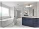 Elegant bathroom featuring marble floors, a soaking tub, and navy blue vanity at 95 Black Walnut Dr # 191, Garner, NC 27529