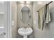 Charming powder room with a pedestal sink, oval mirror, and decorative towel at 1001 Tender Dr, Apex, NC 27502