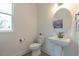 Half bathroom with a pedestal sink, round mirror, and a window providing natural light at 1112 Prominence Dr, Durham, NC 27712