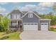 Beautiful two-story home featuring gray siding, stone accents, and a spacious three-car garage at 1112 Prominence Dr, Durham, NC 27712