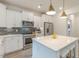 Bright kitchen with stainless steel appliances, white cabinets, and a large quartz island with stool seating at 1112 Prominence Dr, Durham, NC 27712
