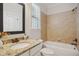 Well-lit bathroom featuring a granite vanity, tiled tub, and updated fixtures at 1212 Sand Pine Dr, Cary, NC 27519